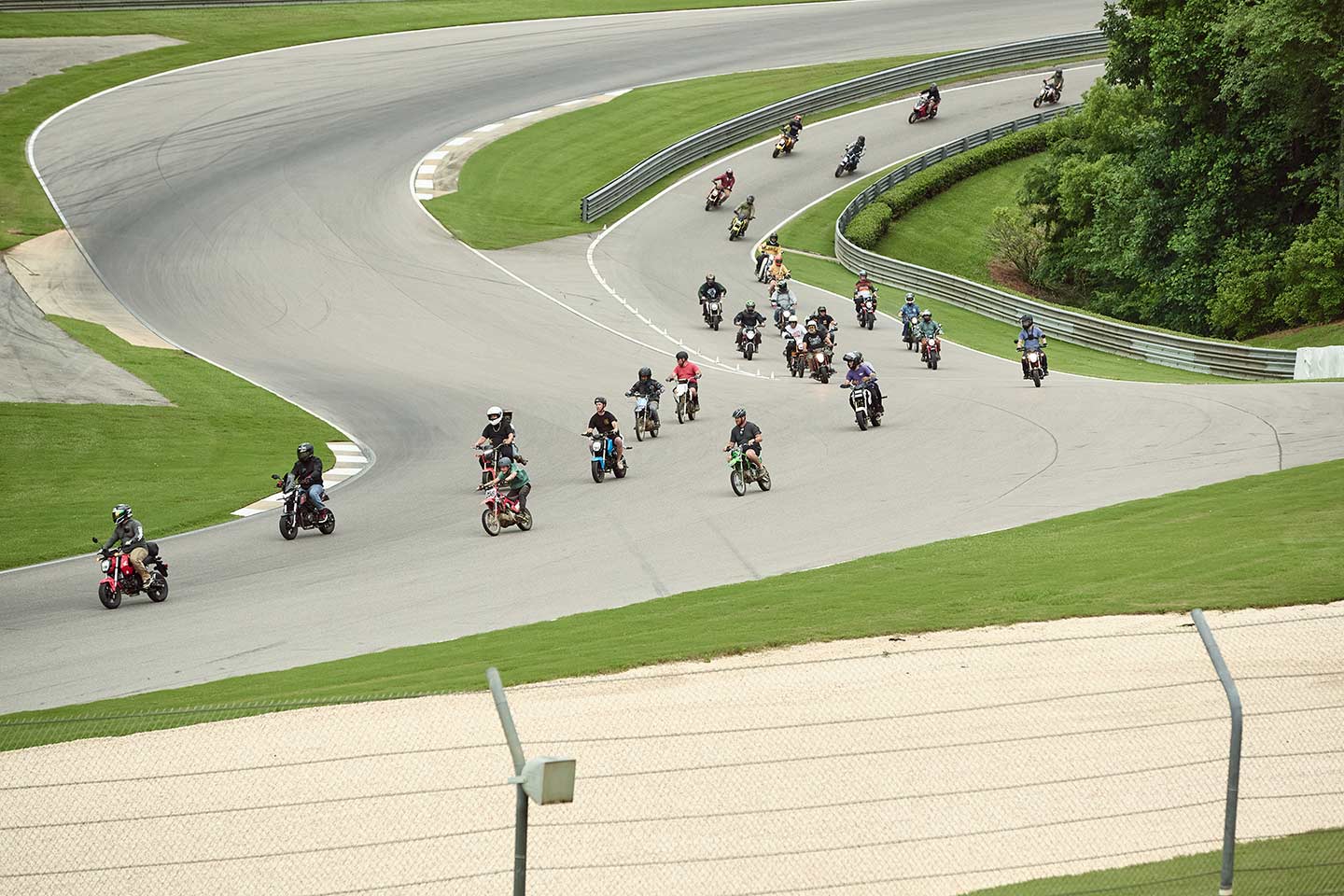 The miniature motorbikes burst forth from the pit lane in a vibrant procession, their tiny engines revving in unison as they take to the track for a thrilling display of speed and agility.